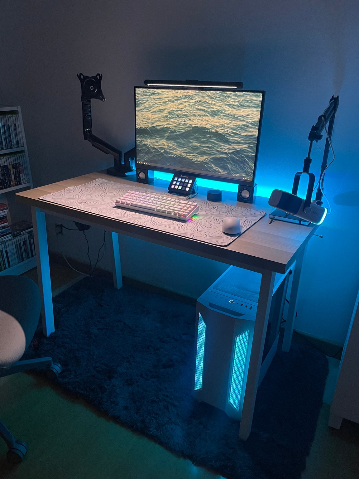 O meu setup de gaming com monitor, teclado, microfone e computador iluminado a azul